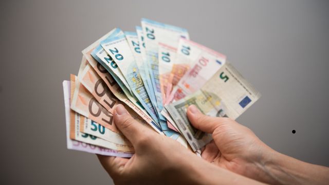 Osoba trzymająca wachlarz banknotów w euro, frankach i innych walutach