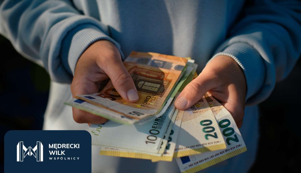 Osoba trzymająca plik banknotów euro