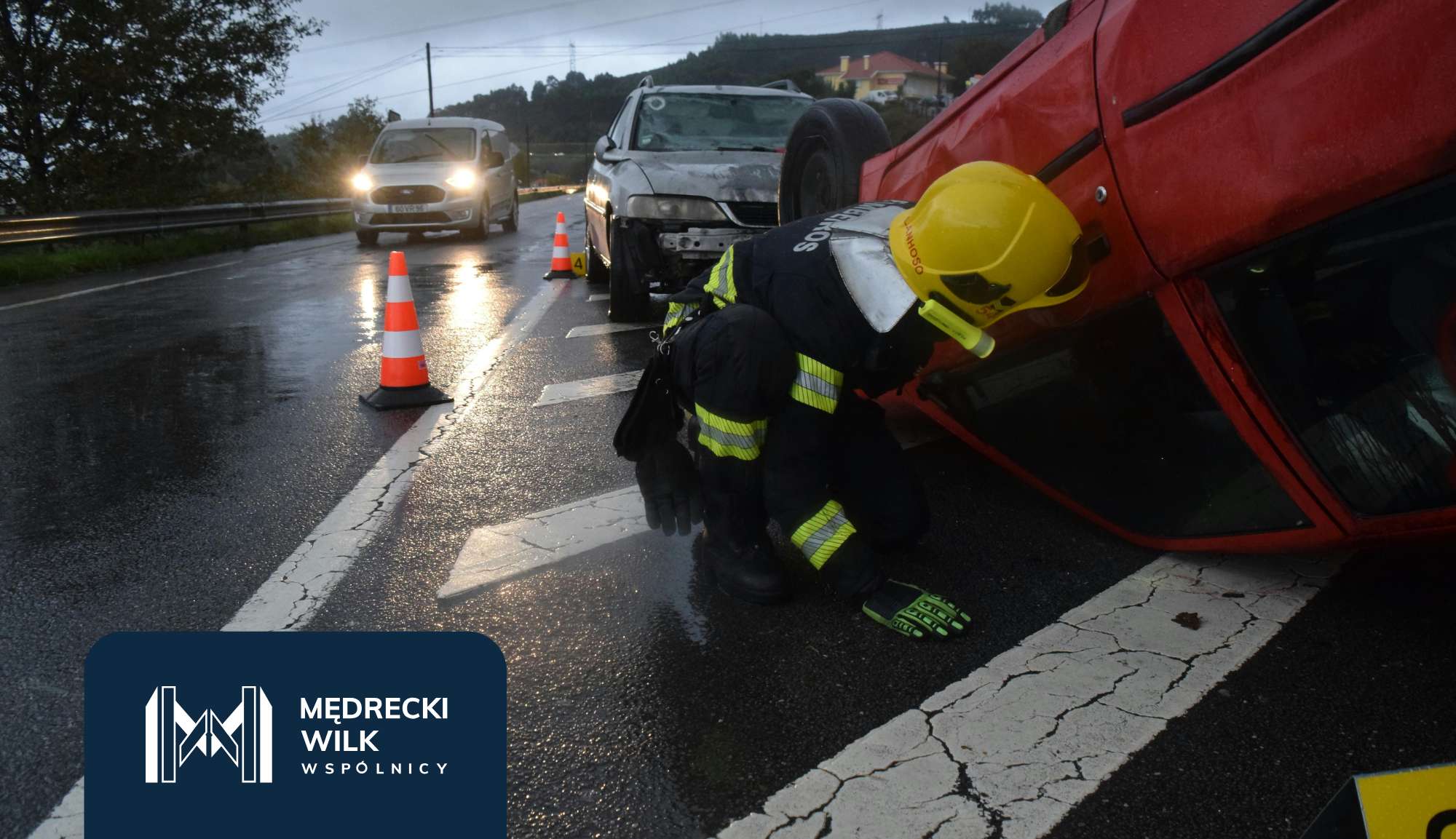 Wypadek samochodowy, zniszczony samochód, poszkodowany, strażak pomagający poszkodowanemu