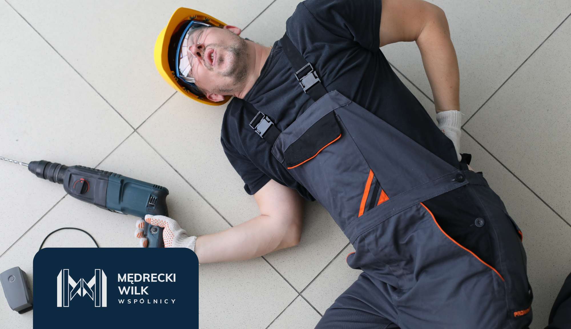 Construction worker in a yellow hard hat and navy overalls lying on tiled floor with a drill nearby; dark blue brand banner in the bottom-left corner.