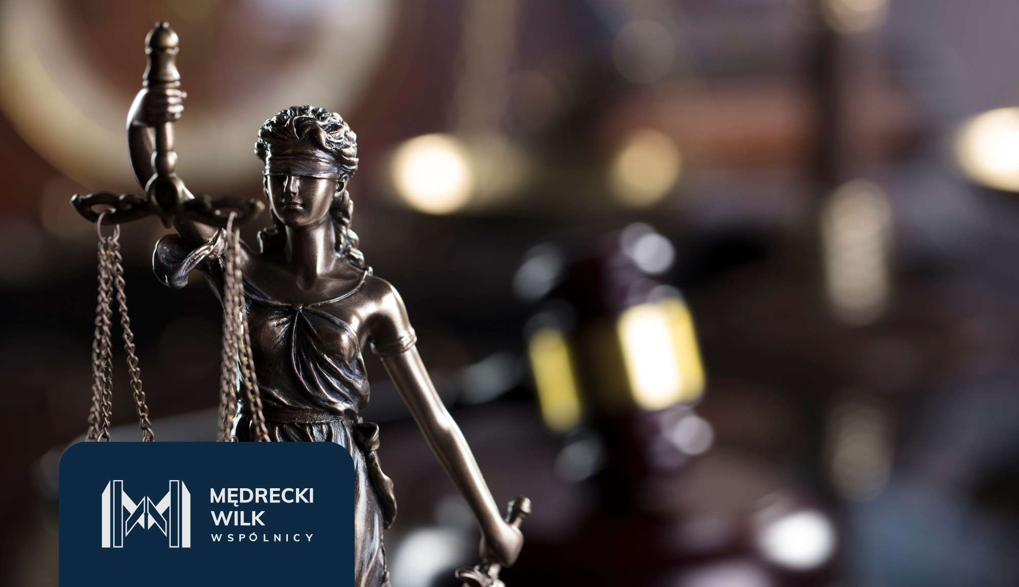 Statue of Lady Justice holding scales in focus, with a blurred office background and a dark blue logo panel in the corner.