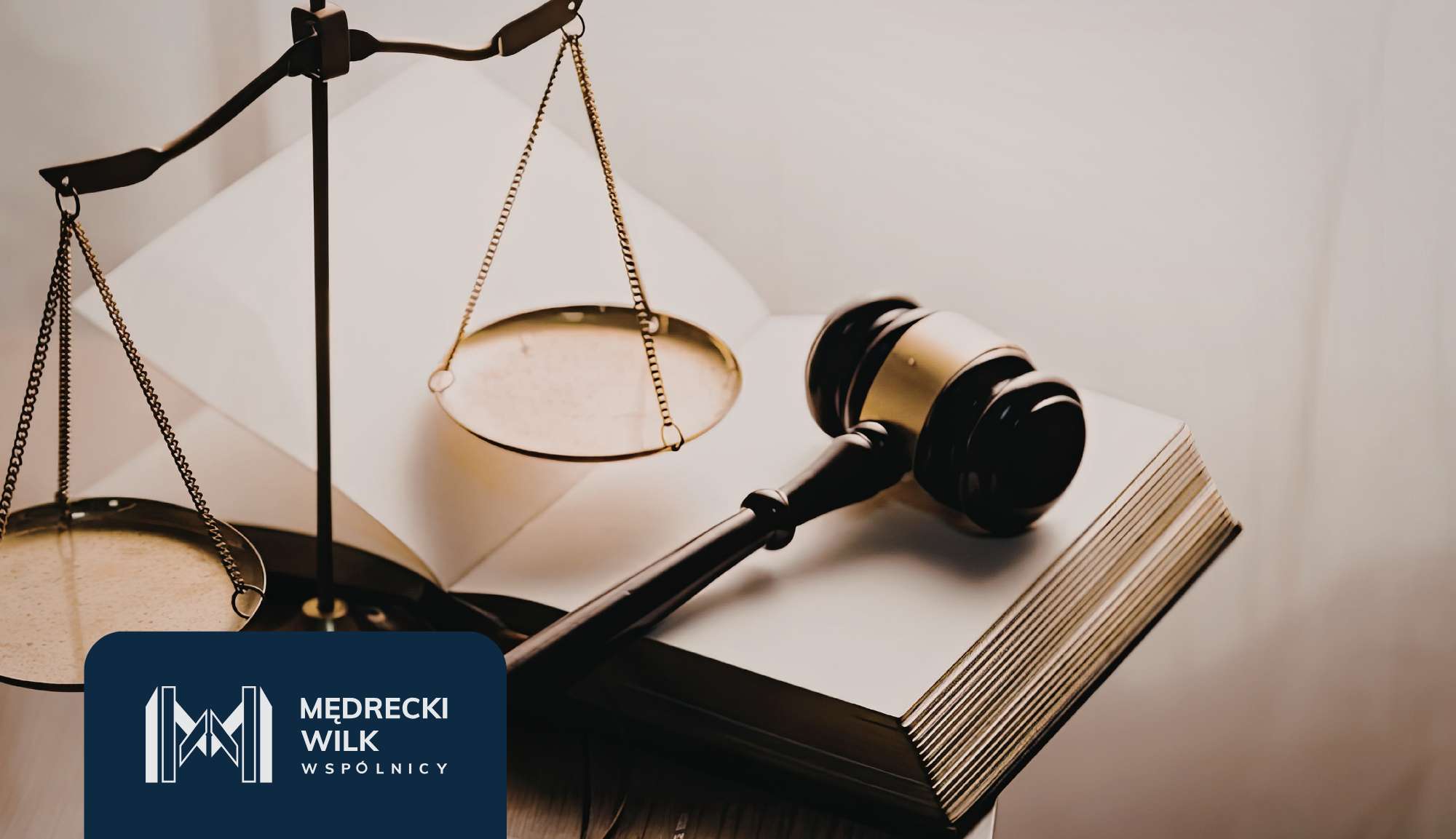 Balance scales and a gavel resting on an open law book, symbolizing justice, with a blue law firm logo in the corner.