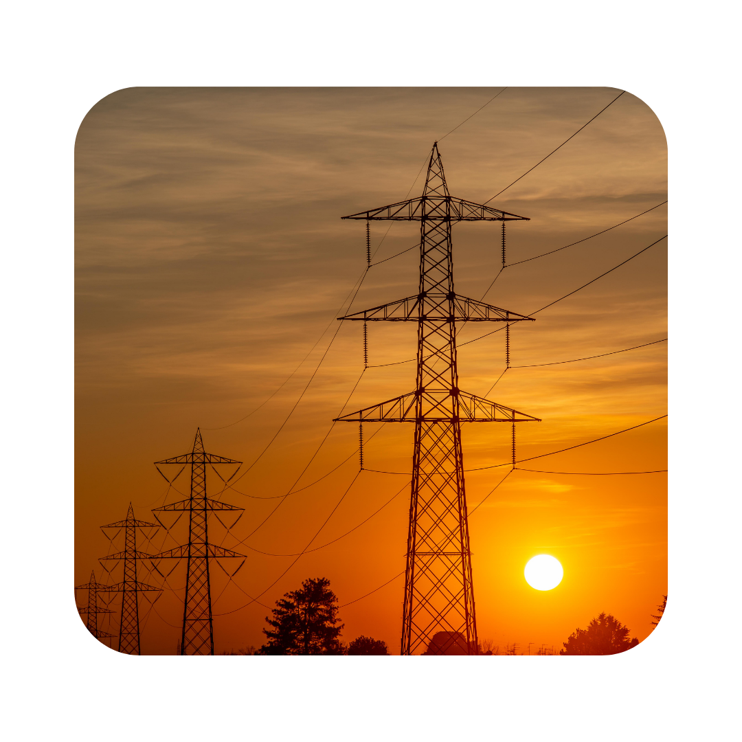 Transmission towers and power lines silhouetted against a orange sunset sky