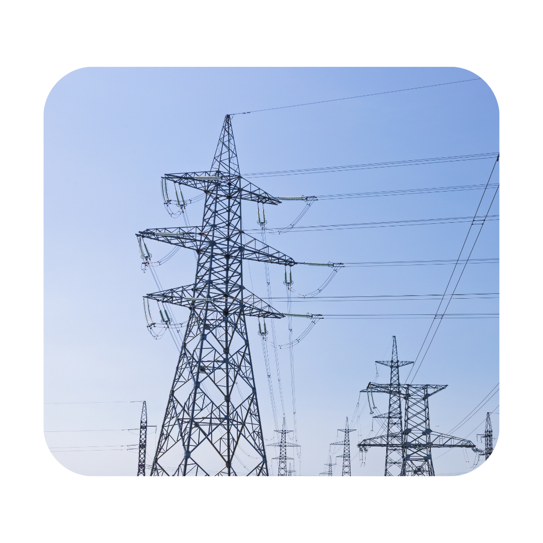 Tall metal electricity transmission tower with multiple crossbars and power lines against a clear blue sky, a rural grid in the background