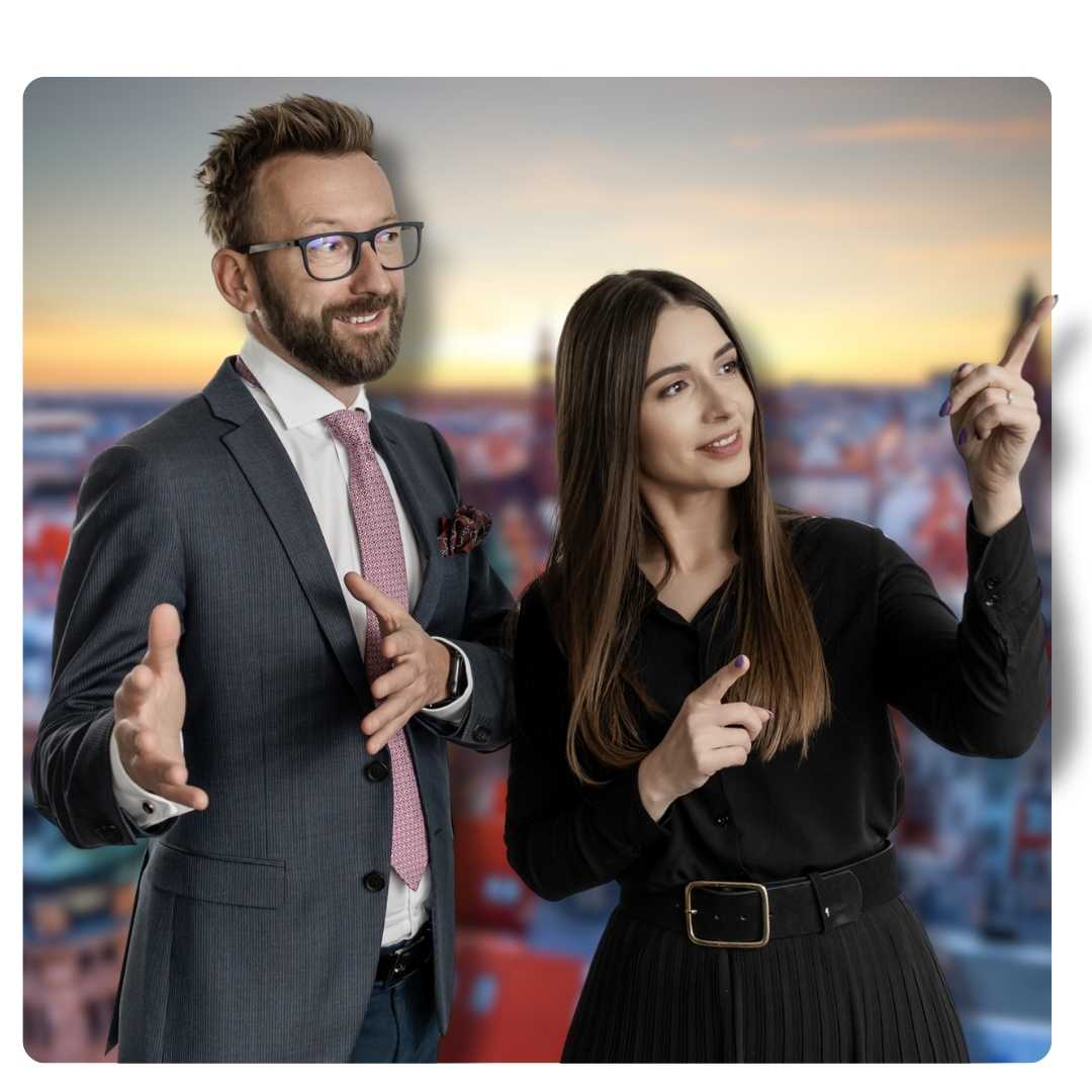 Two businesspeople in professional attire gesture as if presenting with a cityscape backdrop at sunset behind them.