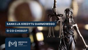Brązowy posąg Temidy z wagą szali, ustawiony z prawej strony kadru na ciemnym, rozmytym tle gabinetu prawnego. Na grafikę nałożone dwa granatowe paski z białymi napisami: „SANKCJA KREDYTU DARMOWEGO” oraz „O CO CHODZI?”. W lewym dolnym rogu logotyp kancelarii Mędrecki Wilk i Wspólnicy.