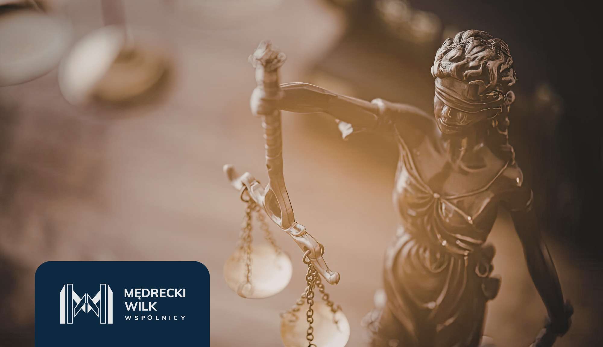 Statue of Lady Justice holding scales, with a blurred background and a dark blue law-firm logo in the bottom-left corner.