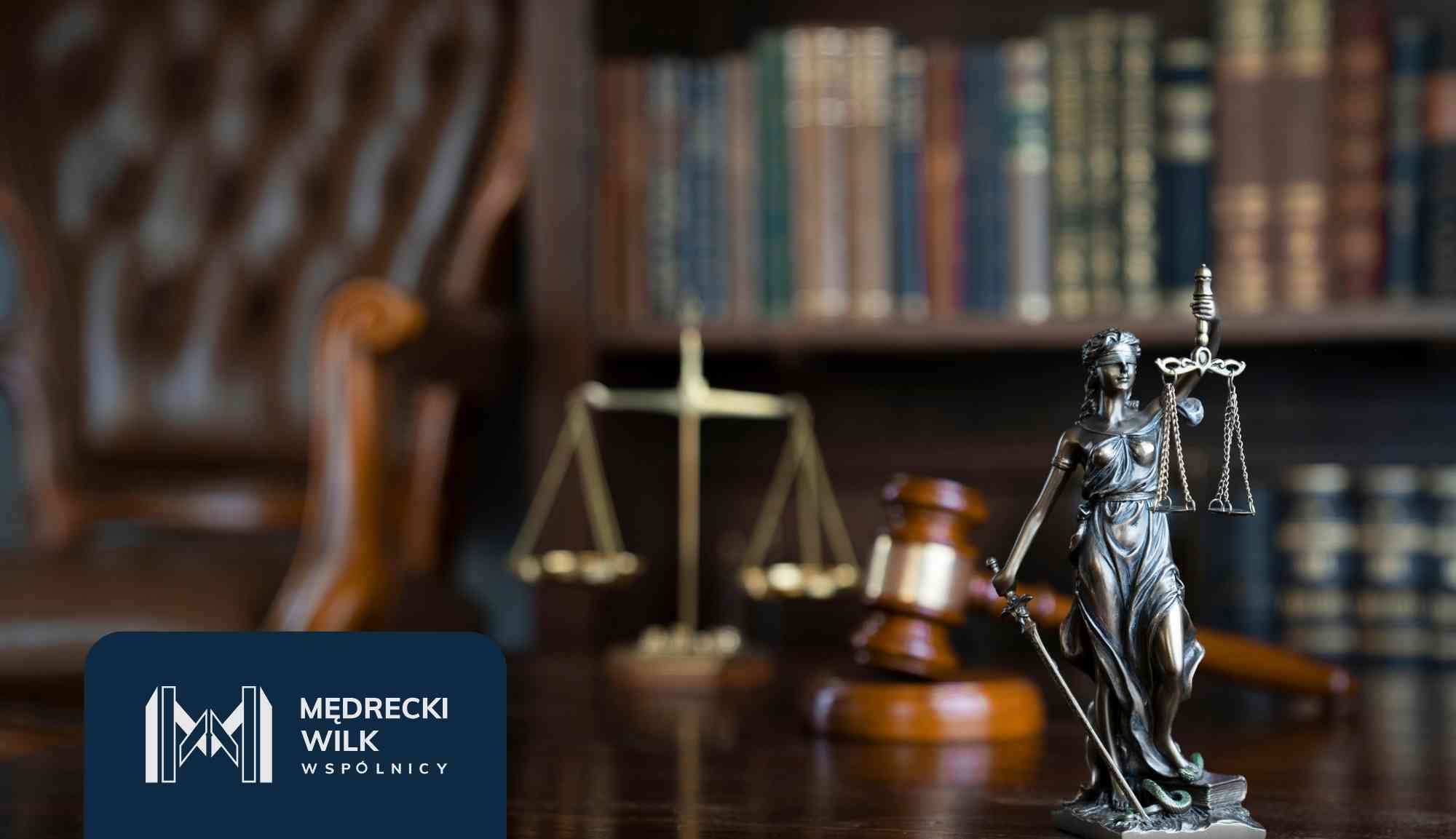 Bronze scales of justice in focus with a blurred person signing documents in the background; law firm branding visible at the bottom left.