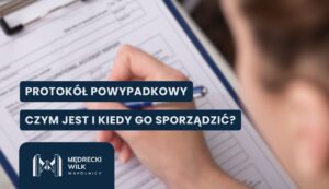 Zbliżenie na dłoń trzymającą długopis i wypełniającą dokument umieszczony na podkładce z klipsem. W prawym rogu widoczny jest rozmyty fragment twarzy osoby piszącej. Na grafikę nałożone dwa granatowe paski z białymi napisami: „PROTOKÓŁ POWYPADKOWY” oraz „CZYM JEST I KIEDY GO SPORZĄDZIĆ?”. W lewym dolnym rogu logotyp kancelarii Mędrecki Wilk i Wspólnicy.