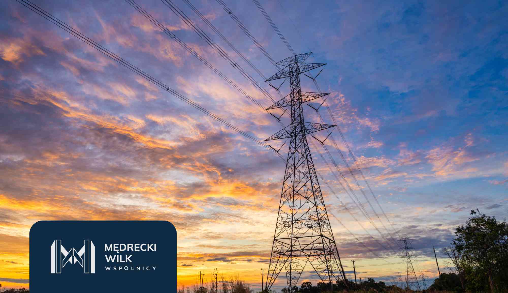 Tall electricity pylon with multiple power lines against a sunset sky at dusk.