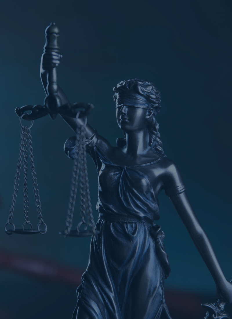 Statue of Lady Justice blindfolded, holding balanced scales against a dark blue background.
