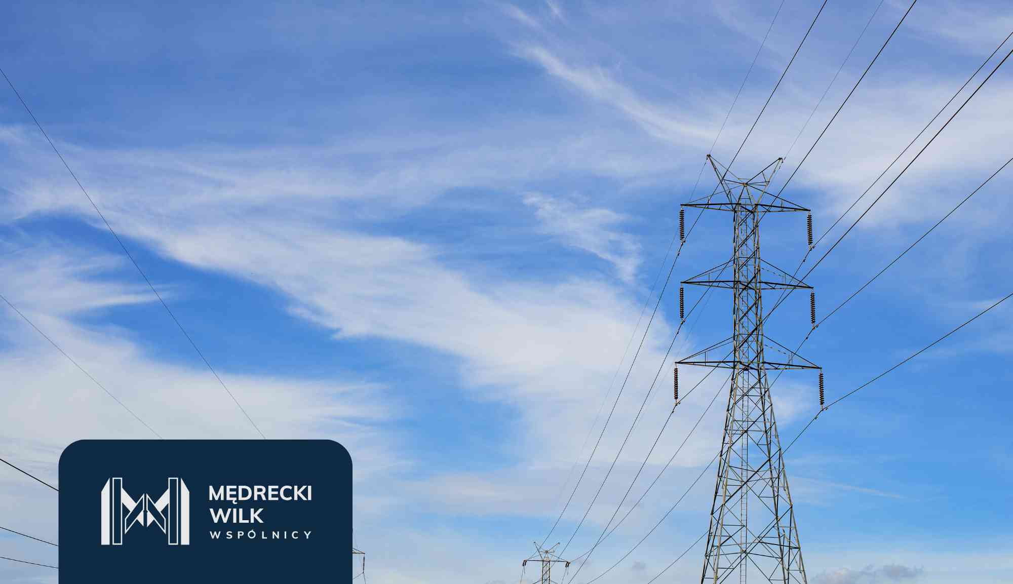 Power lines and tall transmission towers silhouetted against a colorful sunset sky, with a dark blue overlay and company logo in the lower-left corner reading 'Medrecki Wilk Wspólnicy'