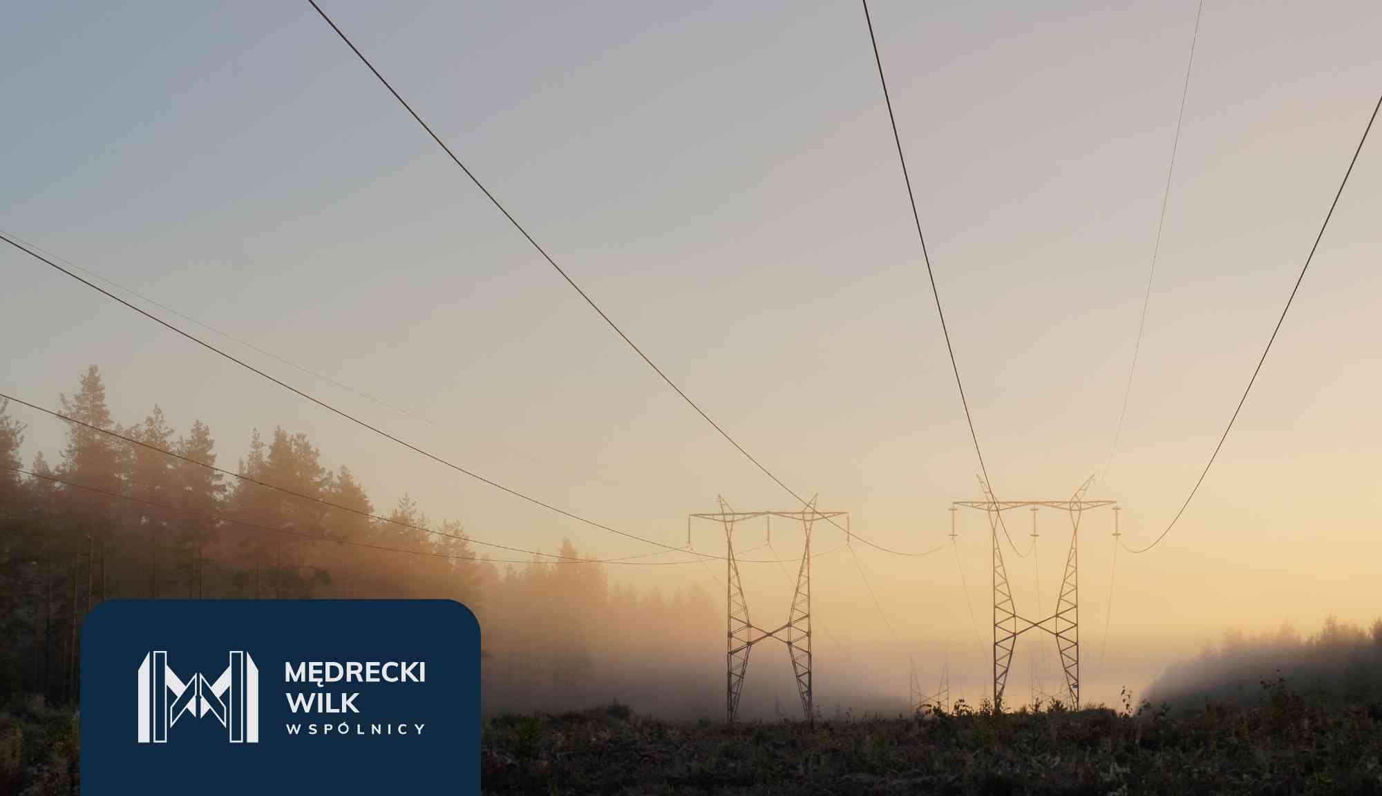 Power lines and tall transmission towers silhouetted against a colorful sunset sky, with a dark blue overlay and company logo in the lower-left corner reading 'Medrecki Wilk Wspólnicy'