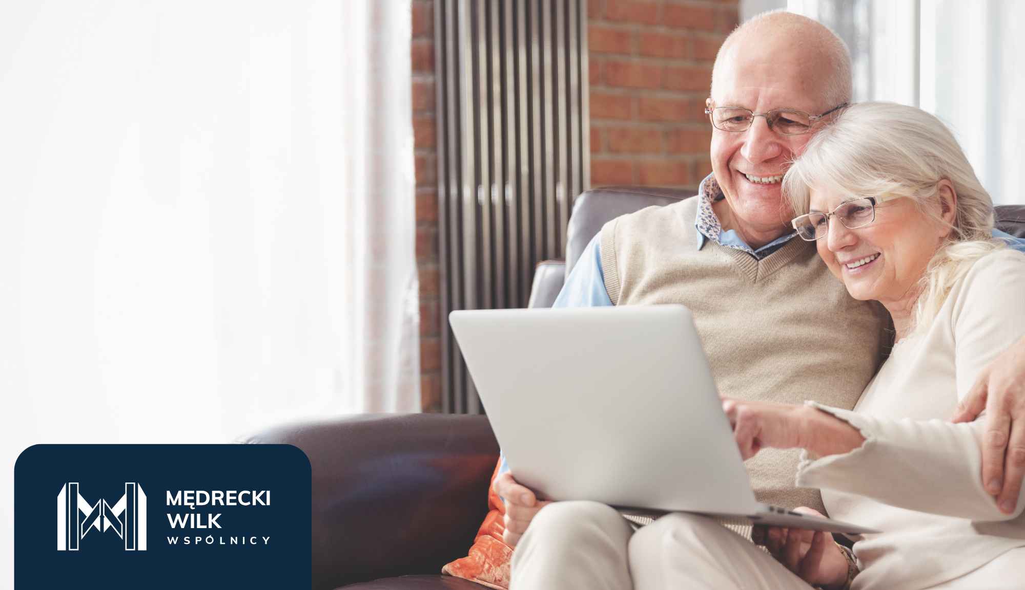 Smiling senior couple sitting on a couch and using a laptop together at home.