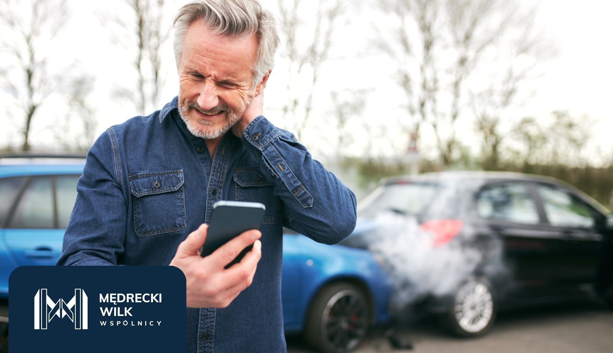 Man on a cellphone with a stressed expression, hand on his head, beside an open car door; a woman stands in the background near another car; dark blue logo panel in the bottom-left corner.